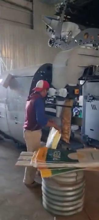 Cosedora automática Camet operando en una línea de embolsado de hortalizas junto a un operario.